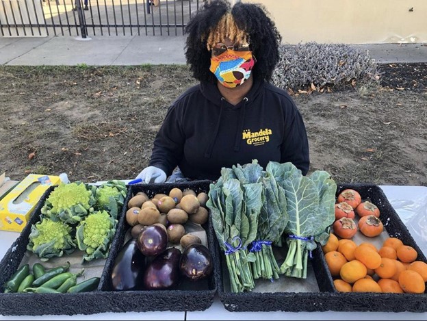 Picture of a Mandela Grocery employee selling fresh produce at Prescott School